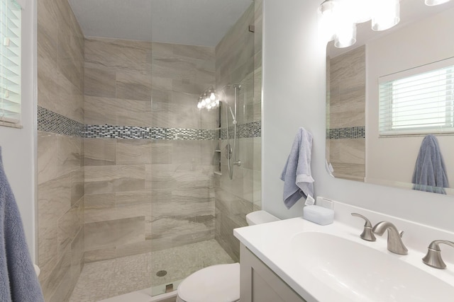 bathroom featuring vanity, a tile shower, and toilet