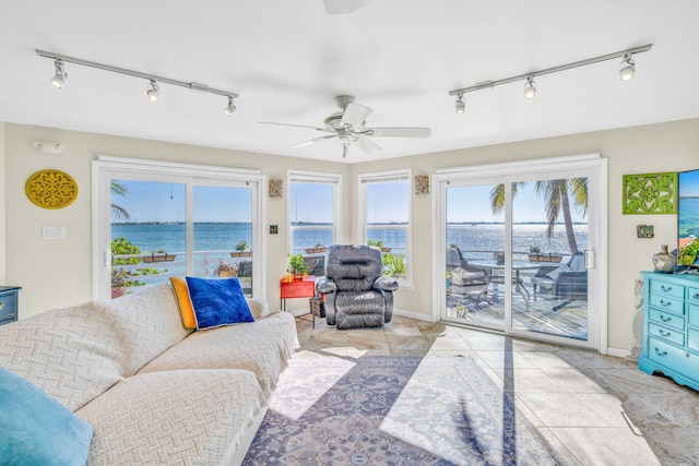 living area featuring tile patterned floors, baseboards, a water view, and a ceiling fan