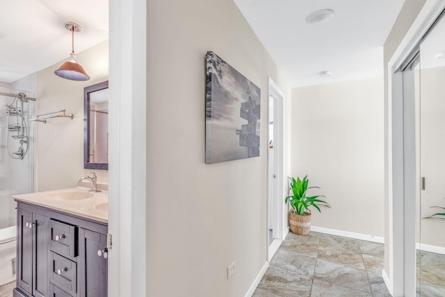 corridor featuring baseboards and a sink