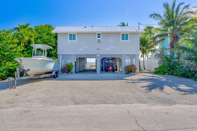 view of front of house with a carport, stairway, dirt driveway, and metal roof