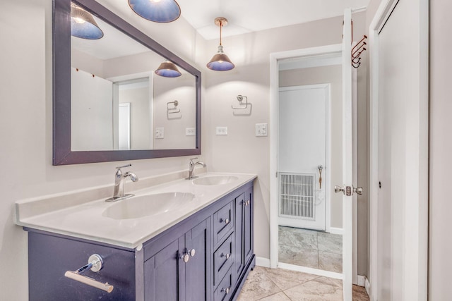 bathroom with double vanity, visible vents, baseboards, and a sink