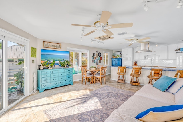 living room featuring visible vents, baseboards, track lighting, and a ceiling fan