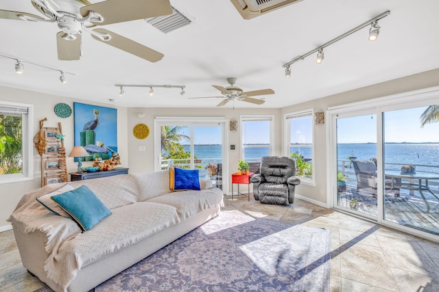 living area featuring baseboards, visible vents, a water view, and ceiling fan