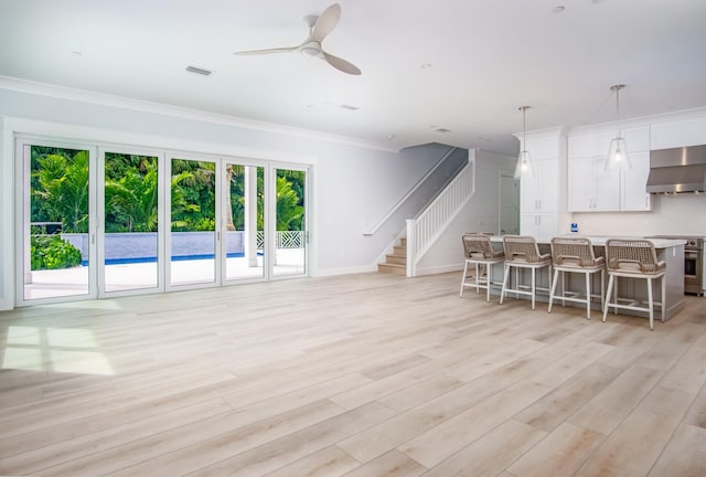 living room featuring ceiling fan, ornamental molding, and light wood-type flooring