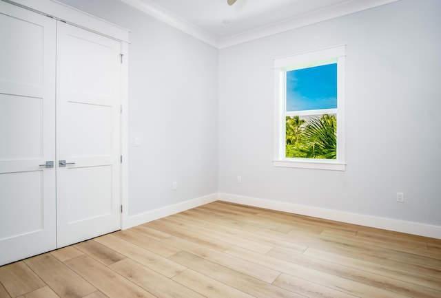 unfurnished bedroom featuring crown molding, light hardwood / wood-style floors, and a closet