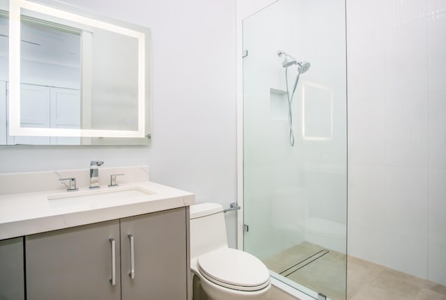 bathroom with tiled shower, vanity, and toilet