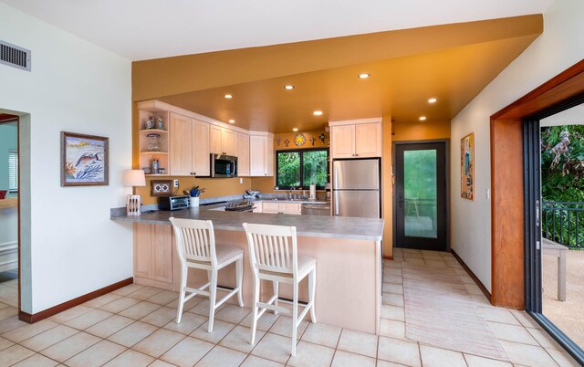 kitchen with stainless steel appliances, kitchen peninsula, a breakfast bar area, and light tile patterned floors