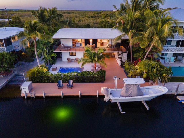 back house at dusk featuring a water view and a patio area