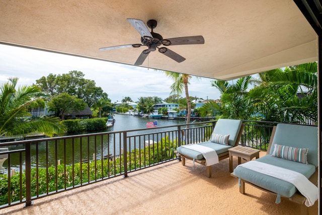 view of patio with a balcony, ceiling fan, and a water view