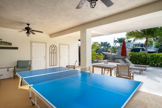 recreation room with ceiling fan and a textured ceiling