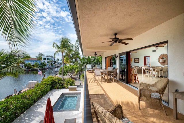 view of swimming pool with a water view, ceiling fan, and a patio area