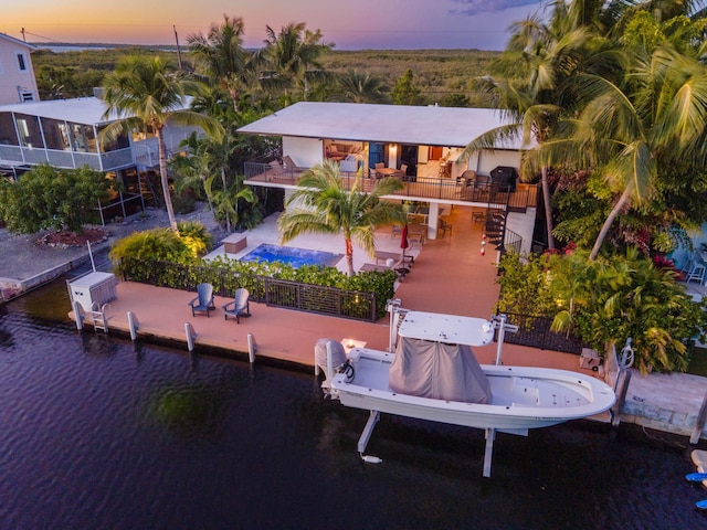 back house at dusk with a patio and a water view