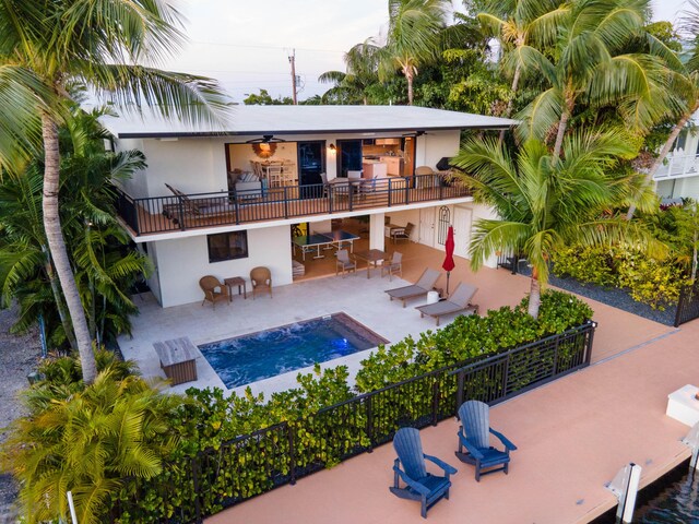 rear view of house featuring a fenced in pool, a balcony, ceiling fan, and a patio area