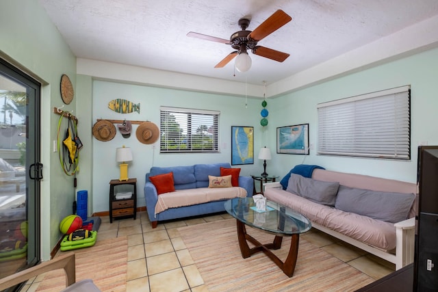 living room featuring light tile patterned floors, a textured ceiling, and ceiling fan