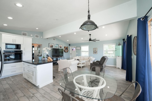 kitchen with lofted ceiling, black microwave, a kitchen island, oven, and white cabinets