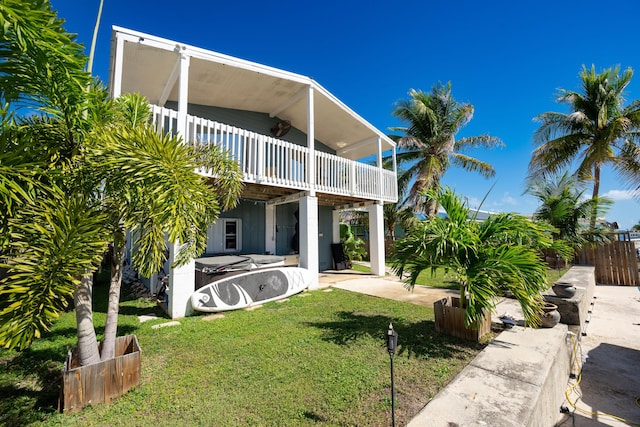 back of property featuring a yard, a patio, and a balcony