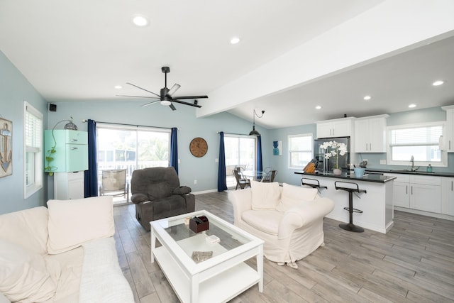 living room with lofted ceiling with beams, sink, a wealth of natural light, and light hardwood / wood-style floors