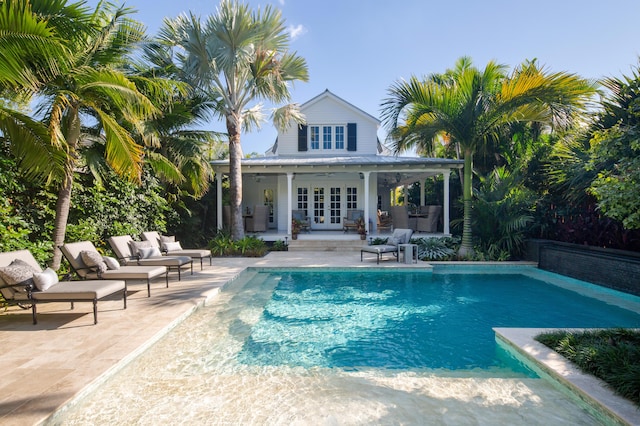 view of pool featuring french doors, a patio, and an outbuilding