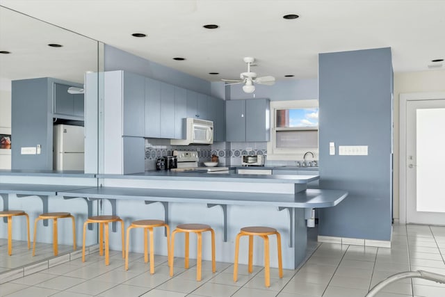 kitchen with sink, decorative backsplash, light tile patterned floors, kitchen peninsula, and white appliances