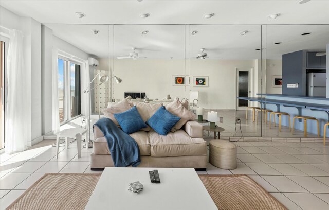 living room featuring light tile patterned floors, a wall unit AC, and ceiling fan