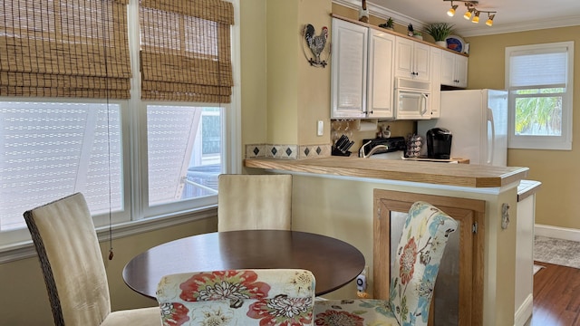 kitchen featuring ornamental molding, dark wood-type flooring, white appliances, and kitchen peninsula