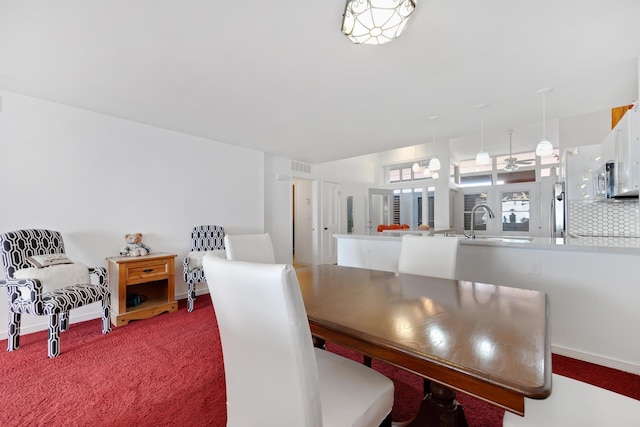 dining room with carpet floors, visible vents, and baseboards