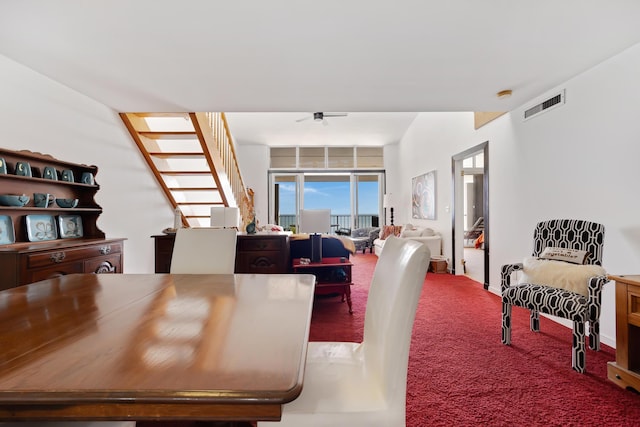 carpeted dining space with a ceiling fan, visible vents, and stairs