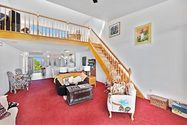 carpeted living area featuring a towering ceiling and stairs