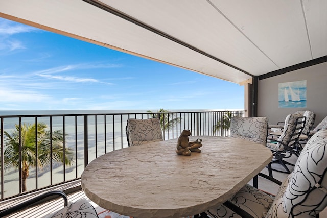 balcony with outdoor dining space and a water view