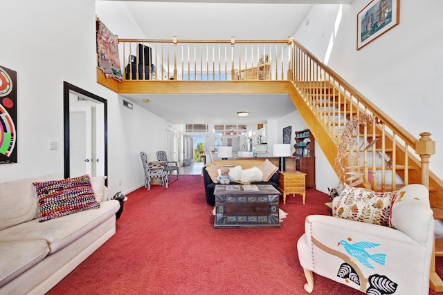 living room featuring a towering ceiling, stairs, and carpet flooring