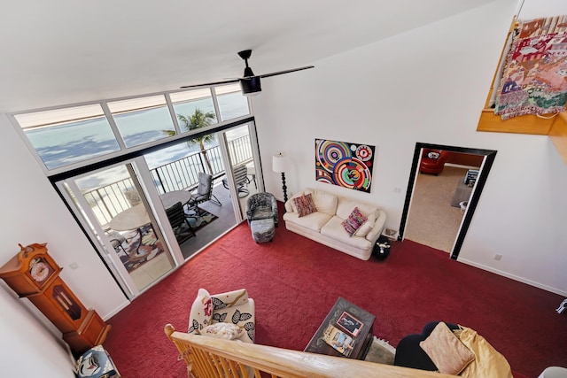 carpeted living area with expansive windows and a ceiling fan