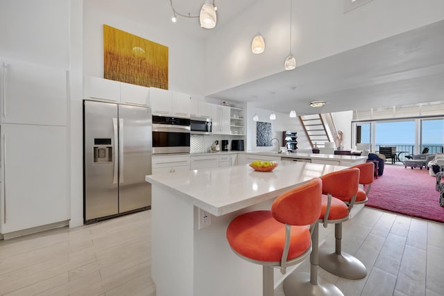 kitchen with stainless steel appliances, light wood-type flooring, open shelves, and light countertops