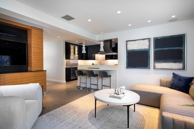 living room with recessed lighting, visible vents, baseboards, and wood finished floors