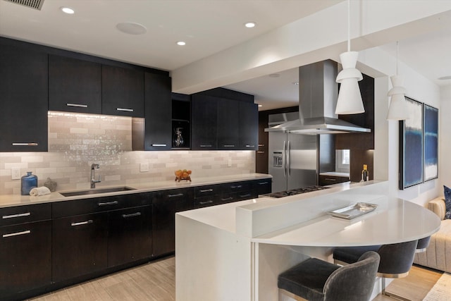 kitchen featuring extractor fan, a sink, light countertops, dark cabinetry, and light wood finished floors