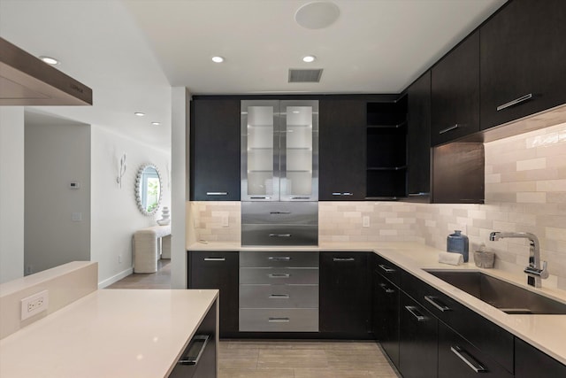 kitchen featuring light countertops, a sink, visible vents, and dark cabinets