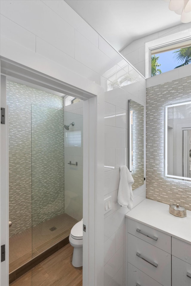 bathroom featuring tile walls, toilet, wood finished floors, walk in shower, and backsplash