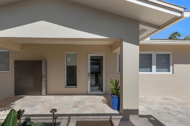 entrance to property featuring a patio and stucco siding