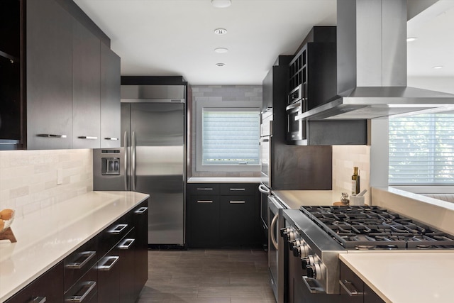 kitchen with tasteful backsplash, modern cabinets, appliances with stainless steel finishes, range hood, and light countertops