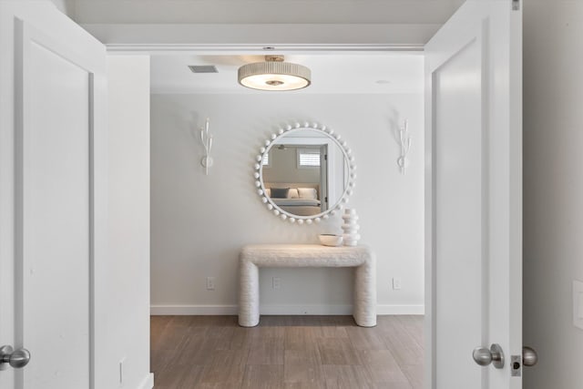 hall featuring baseboards, visible vents, and wood finished floors