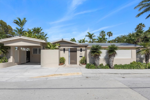 view of front facade with concrete driveway, a carport, and stucco siding