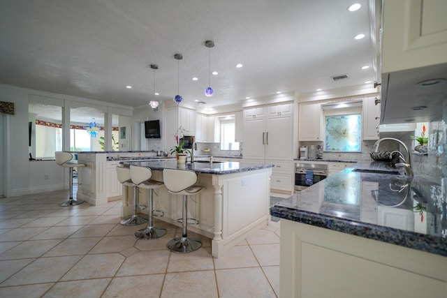 kitchen featuring stainless steel oven, dark stone counters, a breakfast bar, and a kitchen island