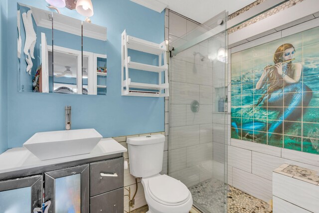 bathroom featuring crown molding, vanity, toilet, and a tile shower