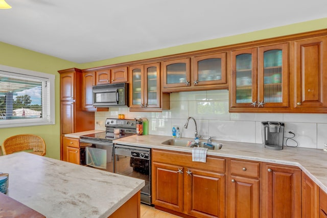 kitchen with tasteful backsplash, sink, black appliances, and light stone countertops