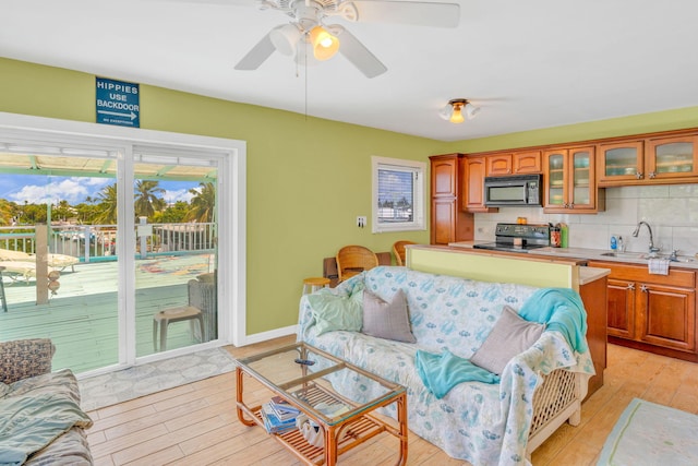 living room with ceiling fan, sink, and light wood-type flooring