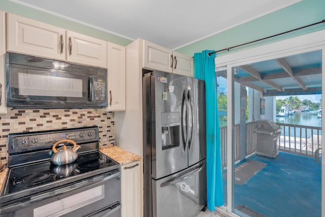 kitchen featuring white cabinetry, a water view, light stone counters, black appliances, and decorative backsplash