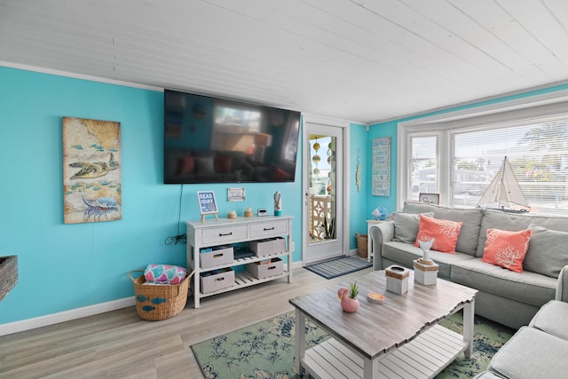 living room featuring crown molding, baseboards, and wood finished floors