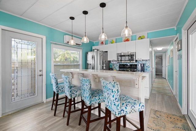 kitchen with appliances with stainless steel finishes, light wood-type flooring, an AC wall unit, and tasteful backsplash