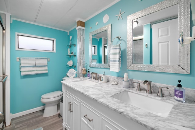 full bathroom with toilet, ornamental molding, a sink, and wood finished floors