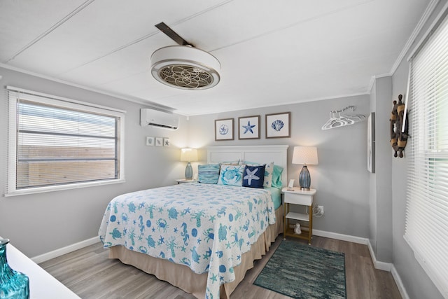 bedroom featuring crown molding, baseboards, wood finished floors, and a wall mounted air conditioner