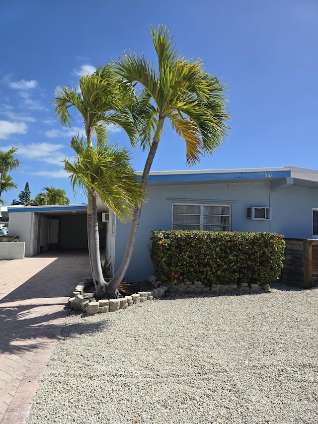 view of property exterior featuring an attached carport, driveway, and stucco siding